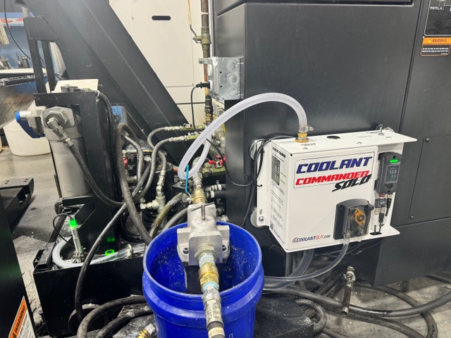 Coolant Commander SOLO plumbed into a CNC machine with a blue concentrate bucket and integrated coolant lines